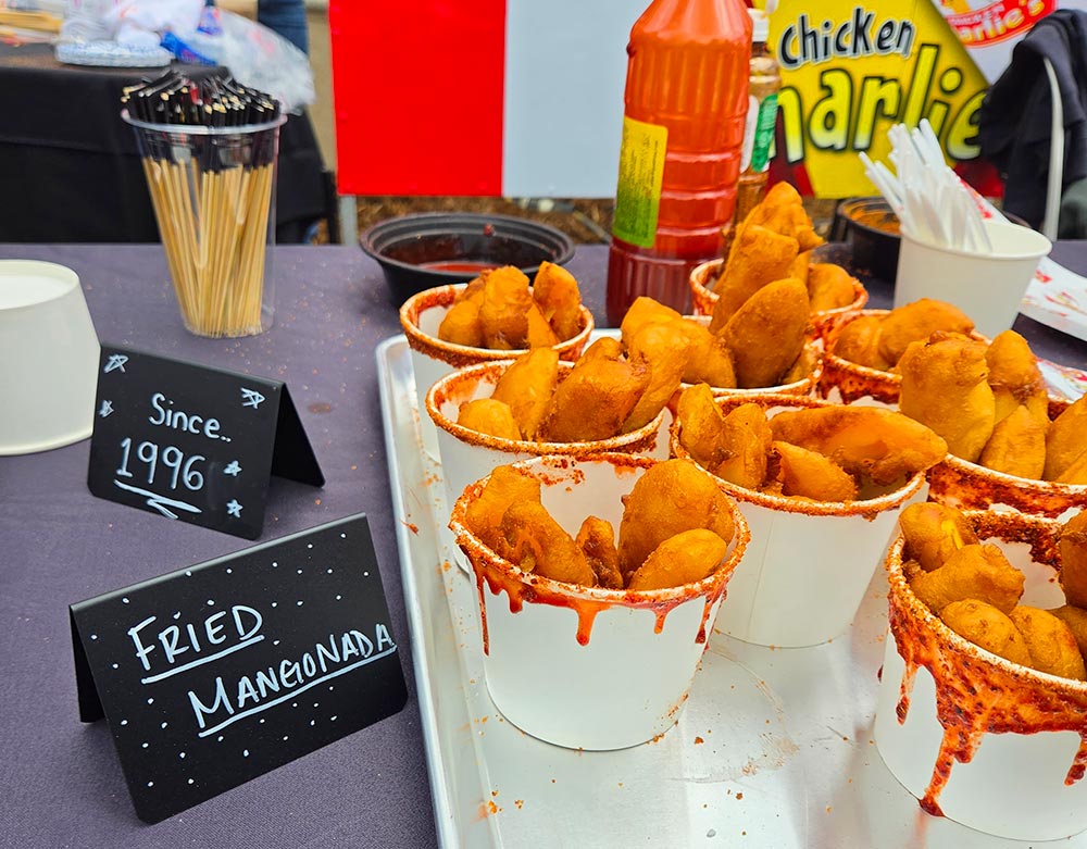 A black topped table with a tray filled with cups of food with sauce dripping on the edges of the cups.
