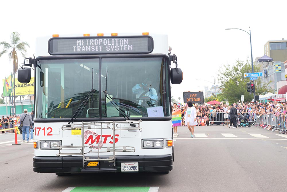 An MTS bus travels along the Pride Parade route with parade spectators watching in the background.