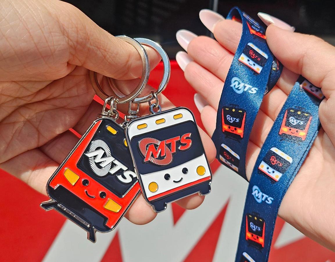 Free Ride Day giveaway items - a bus keychain, a Trolley keychain, and a lanyard held in two separate hands