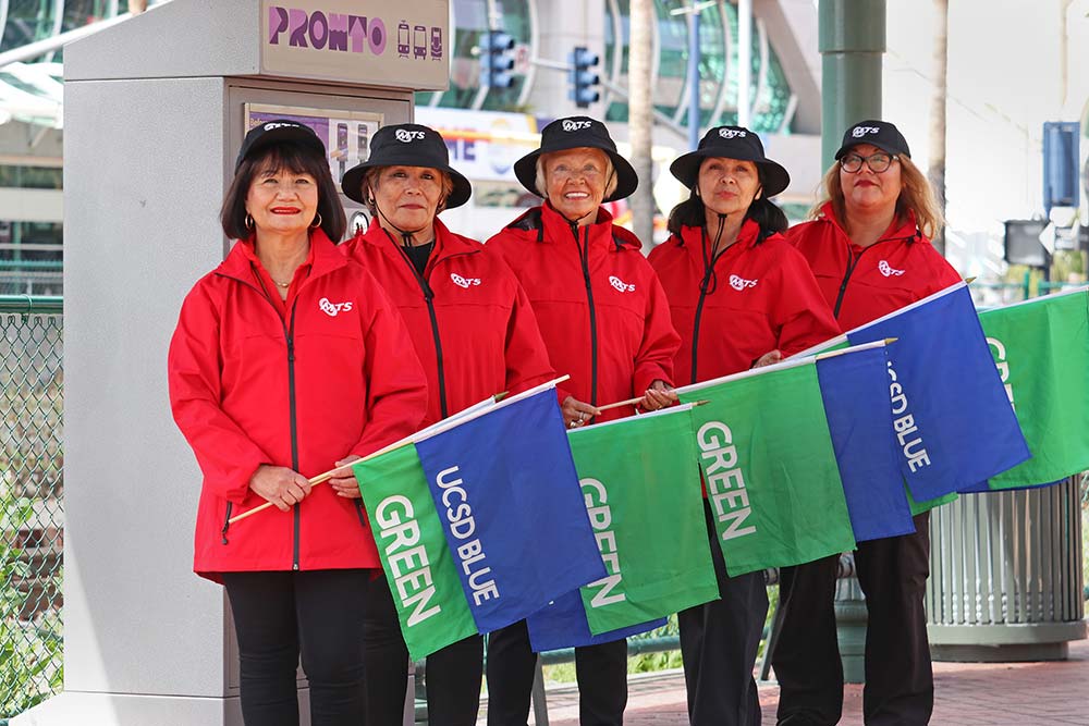 San Diego MTS Passenger Support Representatives hold flags to help indentify Trolleys currently in the station.