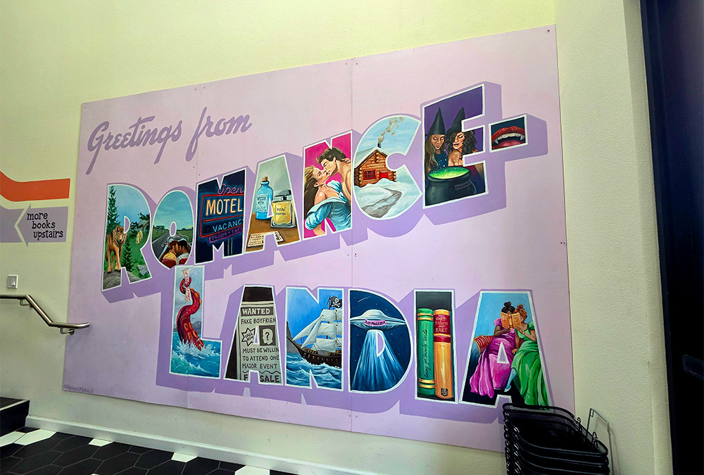 Mural inside of a bookstore that says Greetings from Romance Landia