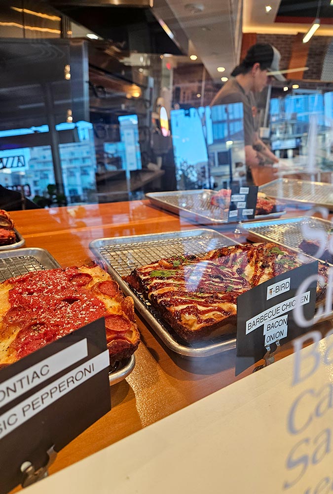 Trays of pizza on a counter inside a restaurant