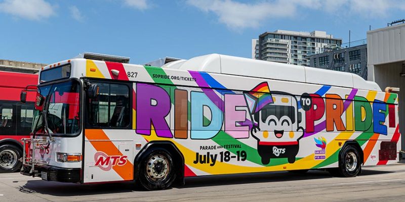 MTS Bus wrapped with a rainbow, the Bus mascot, and says Ride to Pride