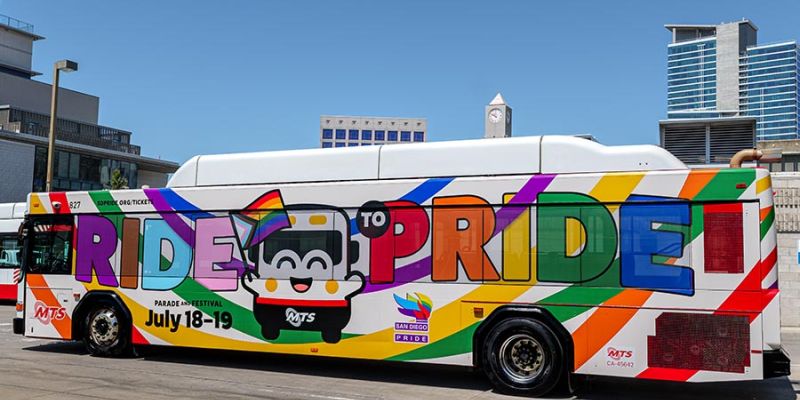 MTS Bus with a special rainbow wrapped around the bus and "Ride to Pride" with the bus mascot on the side