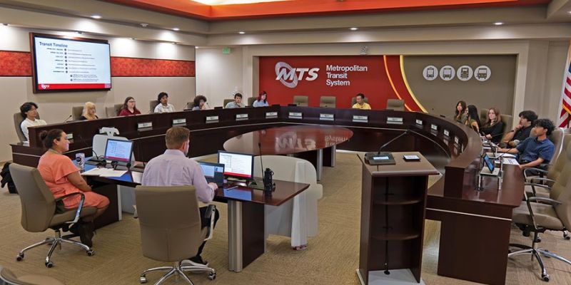 The Youth Advisory Council meets in the MTS Board room, with people sitting around a dais horseshoe platform.