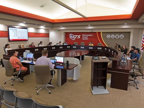 The Youth Advisory Council meets in the MTS Board room, with people sitting around a dais horseshoe platform.