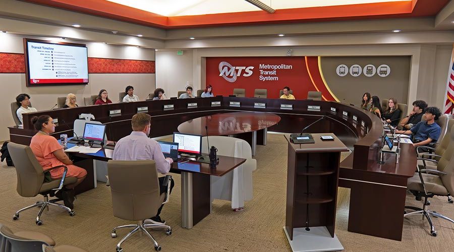 The Youth Advisory Council meets in the MTS Board room, with people sitting around a dais horseshoe platform.