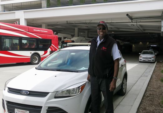 Lewis stands next to a road supervisor car