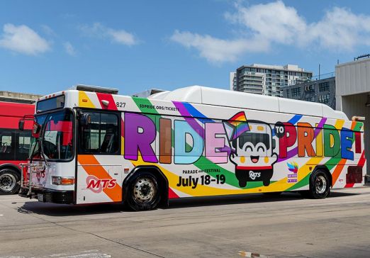 MTS Bus wrapped with a rainbow, the Bus mascot, and says Ride to Pride