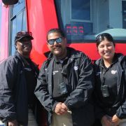 The MTS Homeless Outreach Team stands smiling in front of a San Diego Trolley.