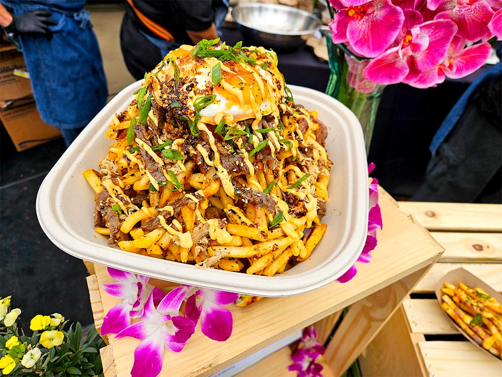 French fries topped with meat and egg with flowers around it.