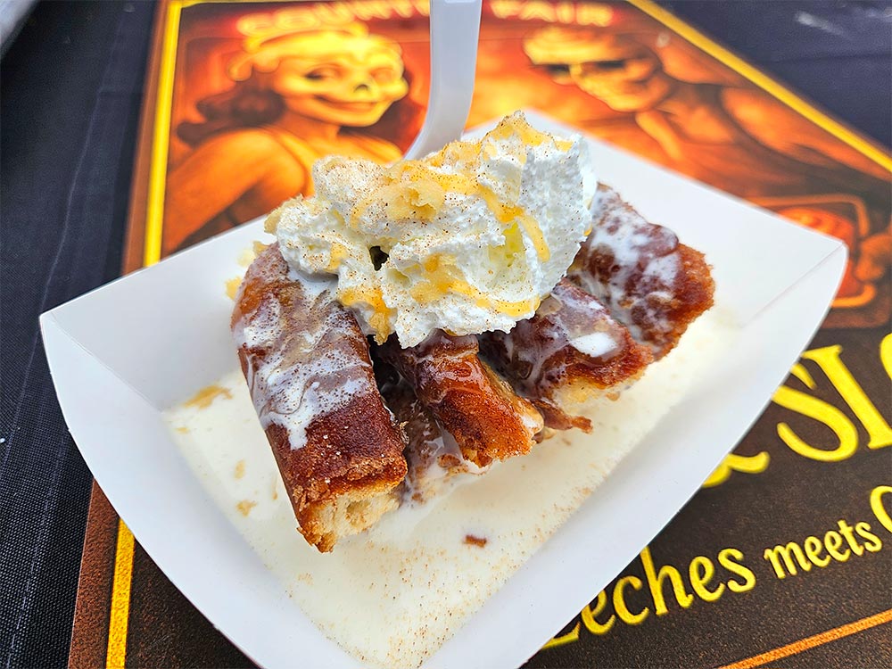 Cinnamon roll with whipped cream sitting in a sauce.
